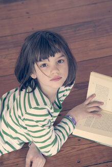 Portrait of little girl reading book at home - LVF000846