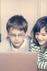 Porträt von Bruder und Schwester, die zu Hause einen Laptop benutzen - LVF000844