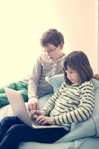 Bruder und Schwester benutzen Laptop zu Hause, lizenzfreies Stockfoto