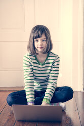Porträt eines kleinen Mädchens mit Laptop zu Hause - LVF000840