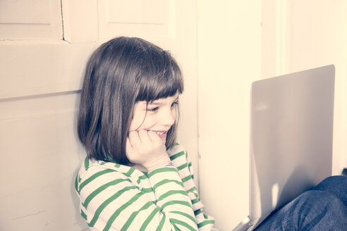 Porträt eines kleinen Mädchens, das zu Hause einen Laptop benutzt - LVF000898
