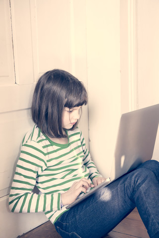 Portrait of little girl using laptop at home stock photo