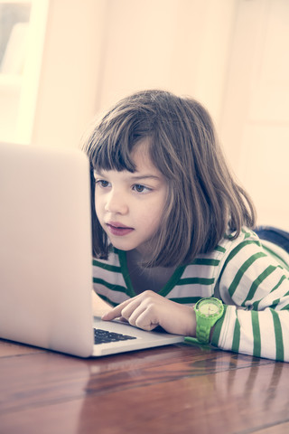 Porträt eines kleinen Mädchens, das zu Hause einen Laptop benutzt, lizenzfreies Stockfoto