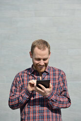 Porträt eines lächelnden jungen Mannes mit Mini-Tablet - BR000167