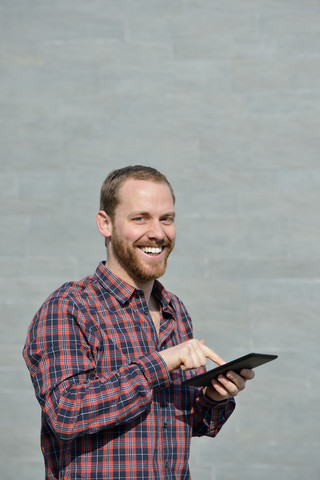 Porträt eines lächelnden jungen Mannes mit Mini-Tablet, lizenzfreies Stockfoto