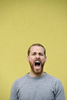 Porträt eines schreienden jungen Mannes vor einem gelben Hintergrund - BR000170