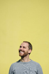 Portrait of laughing young man in front of yellow background - BR000172
