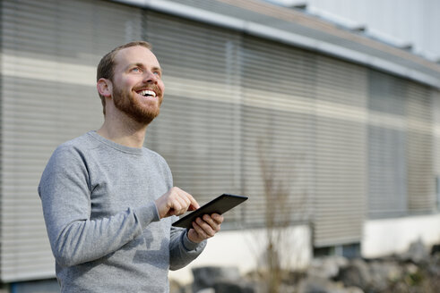Porträt eines glücklichen jungen Mannes mit Mini-Tablet - BR000149