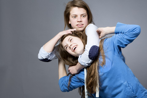 Teenager-Mädchen hat ihre Schwester im Schwitzkasten, lizenzfreies Stockfoto