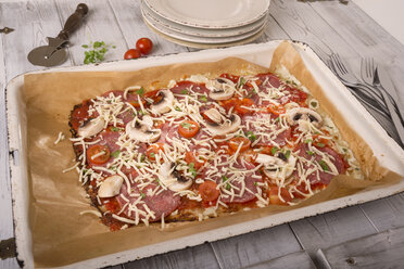 Backblech mit ungebackener Low-Carb-Pizza auf Holztisch - CSTF000169