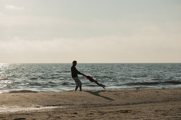 Denmark, Jutland, Lokken, father playing with daughter on beach - JBF000076