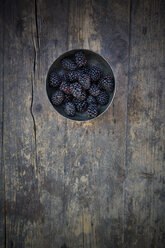 Bowl of blackberries (Rubus sectio Rubus) on wooden table, view from above - LVF000854