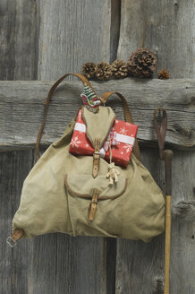 alter Rucksack mit Weihnachtsgeschenk und Dekoration an einer Holzwand - ASF005287