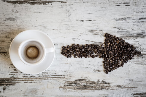 Leere Kaffeetasse mit Essensresten und Pfeil aus Kaffeebohnen auf Holz, Ansicht von oben - SARF000352