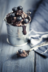 Little metal basket of chocolate ice cream with chocolate sauce and blueberries on wood - SBDF000659