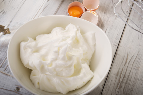 Bowl of beaten egg white on wooden table stock photo