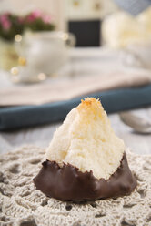 Kokosmakrone mit Schokoladenglasur auf gehäkeltem Tischtuch, Nahaufnahme - CSTF000183