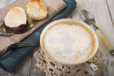 Zwei Kokosmakronen auf Tortenheber und eine Tasse Milchkaffee - CSTF000186