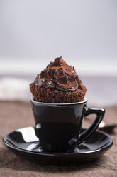 Black cup of chocolate cup cake on brown cloth - MYF000241