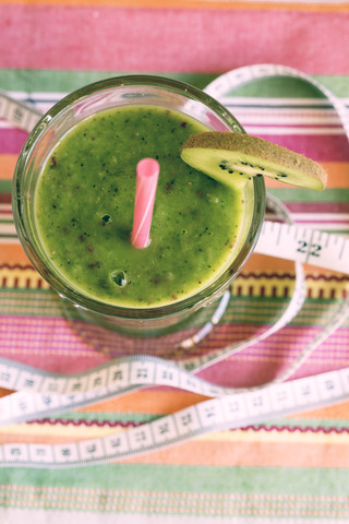 Glas Apfel-Kiwi-Smoothie und Maßband auf Tuch, Blick von oben, lizenzfreies Stockfoto