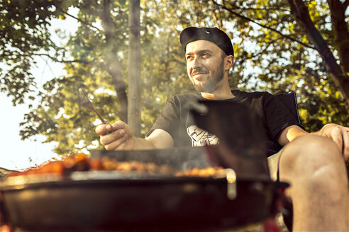 Germany, Hannover, Man having a barbecue - MUMF000073