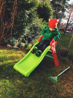 little boy with red hat slips on the slide - AFF000048