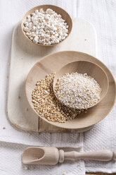 Bowls of puffed buckwheat, amaranth and quinoa on kitchen board and towel - MYF000260