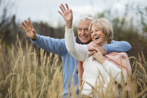 Porträt eines glücklichen älteren Paares, das einen Spaziergang macht und jemanden begrüßt - WESTF019210