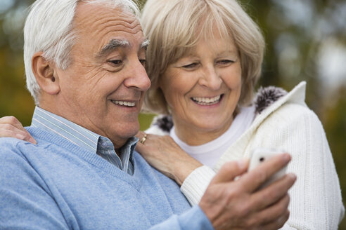 Porträt eines lächelnden älteren Paares, das ein Selbstporträt auf seinem Smartphone betrachtet - WESTF019216