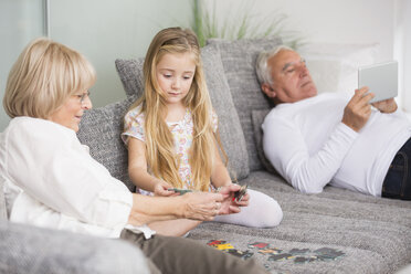 Ältere Frau und Enkelin spielen zusammen auf dem Sofa im Wohnzimmer - WESTF019175