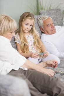 Ältere Frau und Enkelin spielen zusammen auf dem Sofa im Wohnzimmer - WESTF019174