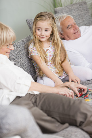 Ältere Frau und Enkelin spielen zusammen auf dem Sofa im Wohnzimmer, lizenzfreies Stockfoto