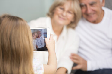 Kleines Mädchen fotografiert ihre Großeltern mit digitalem Tablet zu Hause - WESTF019166