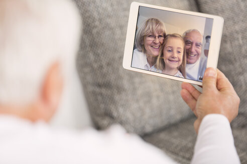 Seniorin schaut auf digitales Tablet mit Familienporträt - WESTF019162