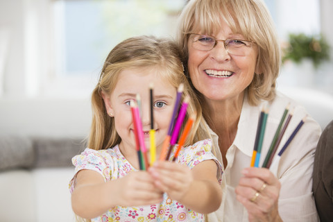 Ältere Frau und Enkelin zeigen Buntstifte, lizenzfreies Stockfoto