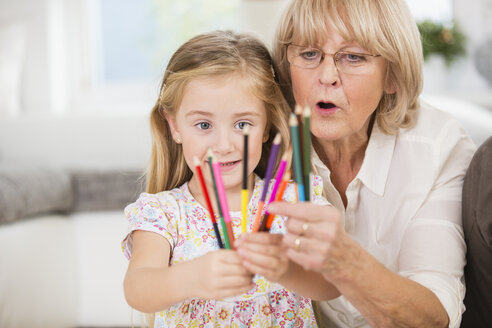 Ältere Frau und Enkelin zeigen Buntstifte - WESTF019157