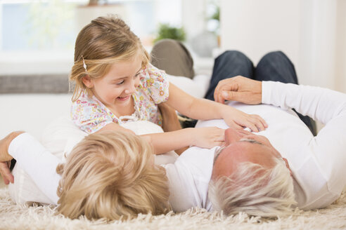 Älteres Ehepaar und Enkelin liegen zu Hause auf dem Boden - WESTF019148