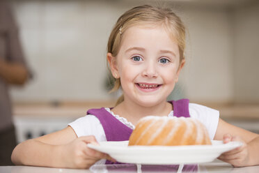 Porträt eines lächelnden kleinen Mädchens, das einen Teller mit Ringkuchen hält - WESTF019134