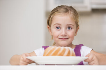 Porträt eines lächelnden kleinen Mädchens, das einen Teller mit Ringkuchen hält - WESTF019133