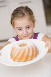 Porträt eines lächelnden kleinen Mädchens, das einen Teller mit Ringkuchen nimmt - WESTF019132