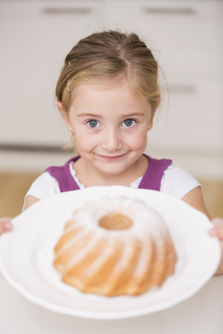 Porträt eines lächelnden kleinen Mädchens, das einen Teller mit Ringkuchen hält, lizenzfreies Stockfoto