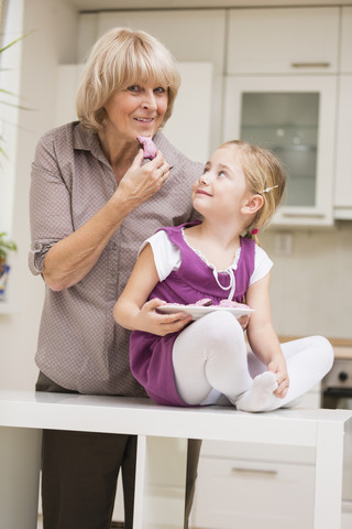 Kleines Mädchen und ihre Großmutter in der Küche, lizenzfreies Stockfoto