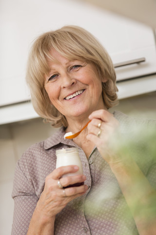 Porträt einer älteren Frau mit einem Glas Joghurt, lizenzfreies Stockfoto