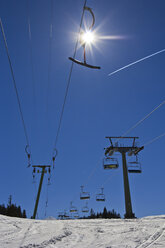 Germany, Bavaria, Winklmoosalm, T-bar lift, chair lift and vapour trail, against the sun - YF000076