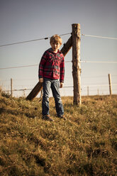 Junge steht auf einer Wiese vor einem Zaun - SARF000420