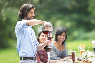Man pouring red wine on a garden party - ABF000544