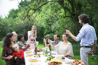 Mann stößt mit Rotwein auf einer Gartenparty an - ABF000549