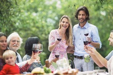 Couple holding glasses of red wine on a garden party - ABF000551