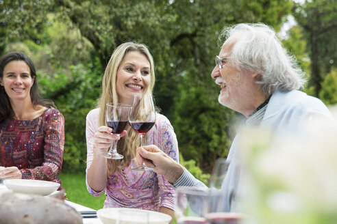 Frau und älterer Mann stoßen mit Weingläsern auf einer Gartenparty an - ABF000540