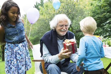 Großvater erhält Geschenke auf Geburtstagsfeier im Garten - ABF000563